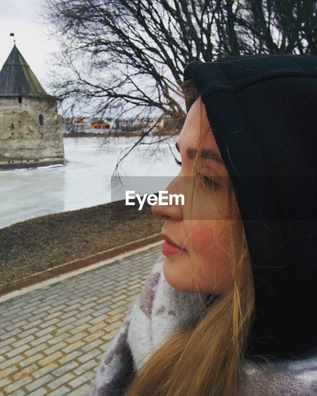 CLOSE-UP PORTRAIT OF WOMAN WITH WATER IN BACKGROUND