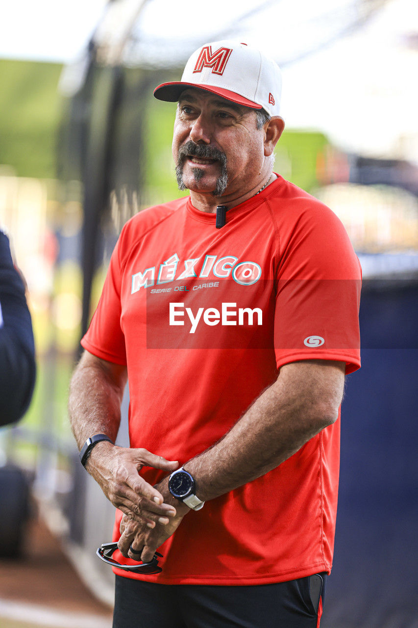 adult, men, sports, one person, clothing, person, occupation, athlete, standing, working, mature adult, day, focus on foreground, hat, red, industry, waist up, fashion accessory, business finance and industry, outdoors, holding, senior adult, seniors, architecture, endurance sports