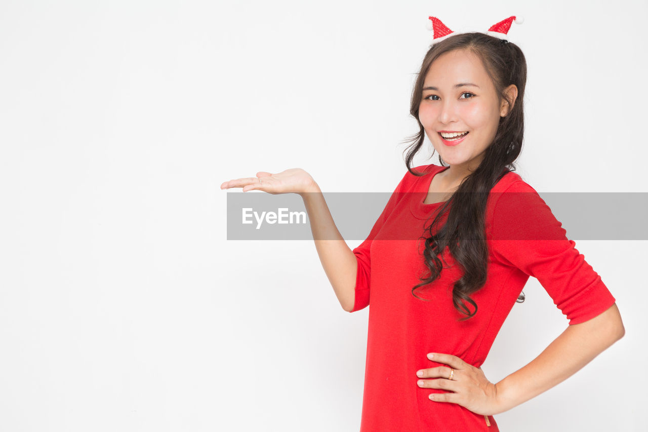 red, women, one person, smiling, studio shot, happiness, portrait, white background, adult, emotion, young adult, indoors, cheerful, looking at camera, clothing, copy space, positive emotion, celebration, long hair, fashion, waist up, hairstyle, female, cut out, gesturing, teeth, lifestyles, smile, pink, standing, hand, joy, enjoyment, event, fun, carefree, cute, dress, brown hair, front view