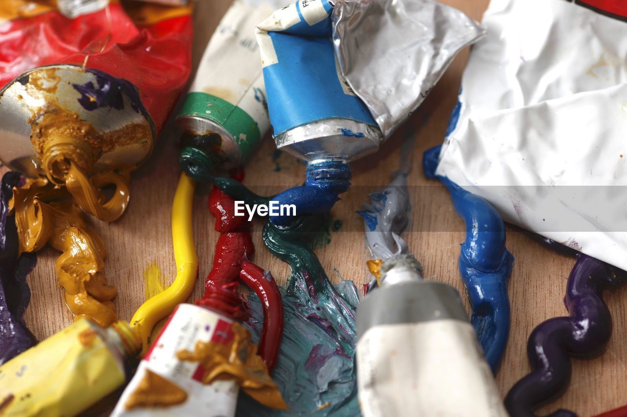 High angle view of colorful paints with tubes on table at workshop