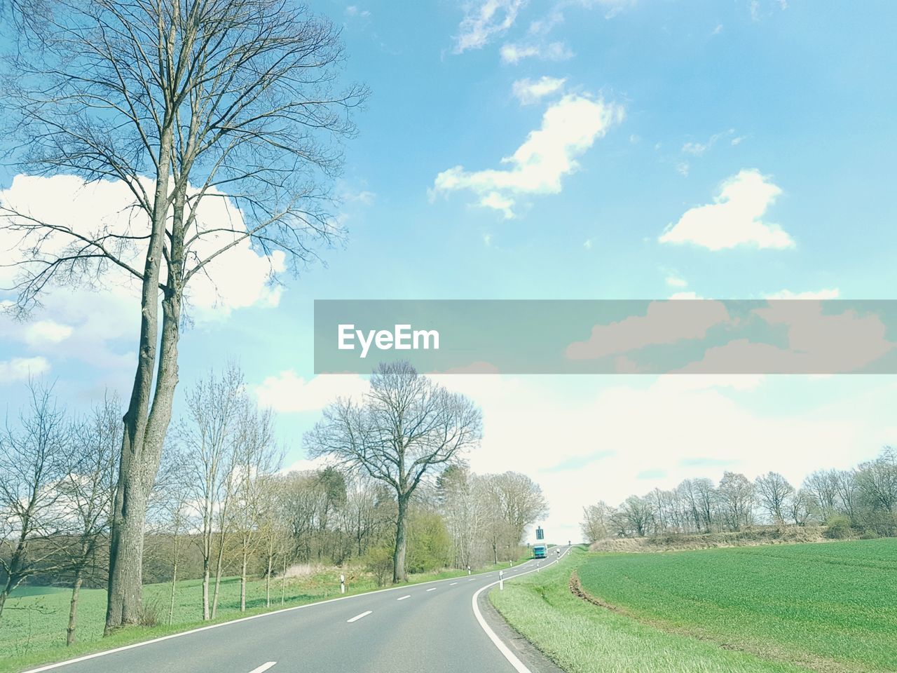 EMPTY ROAD ALONG TREES ON FIELD