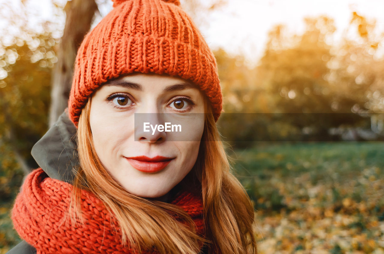 Autumn portrait of stylish woman in orange warm knitted hat and orange scarf. romantic look