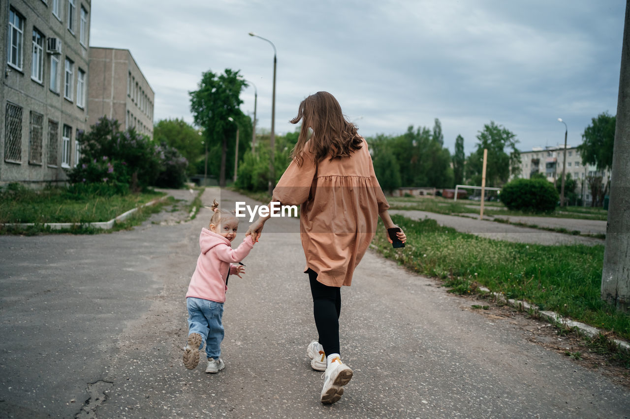 Mom with toddler daughter running on the track outdoors