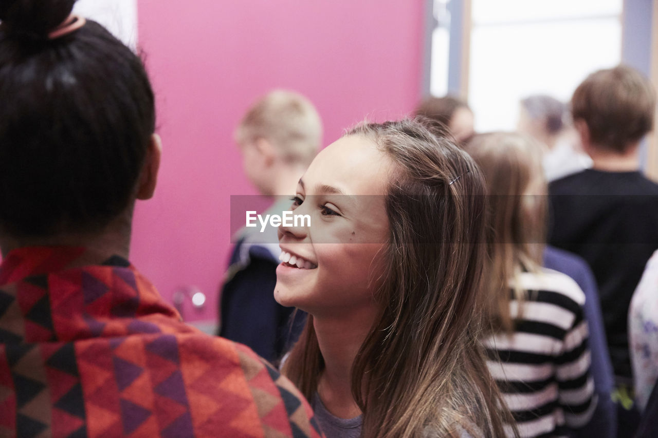 Smiling girl with female friend in school cafeteria