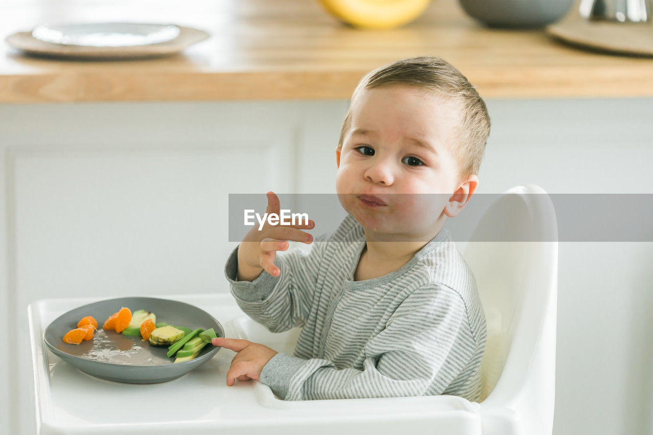portrait of cute girl eating food in kitchen