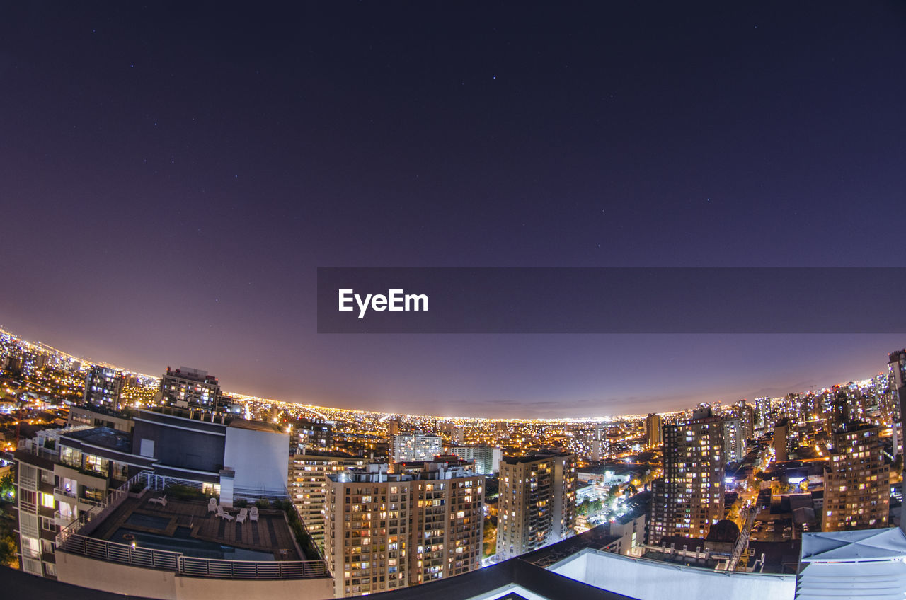 HIGH ANGLE VIEW OF ILLUMINATED BUILDINGS AGAINST SKY DURING NIGHT