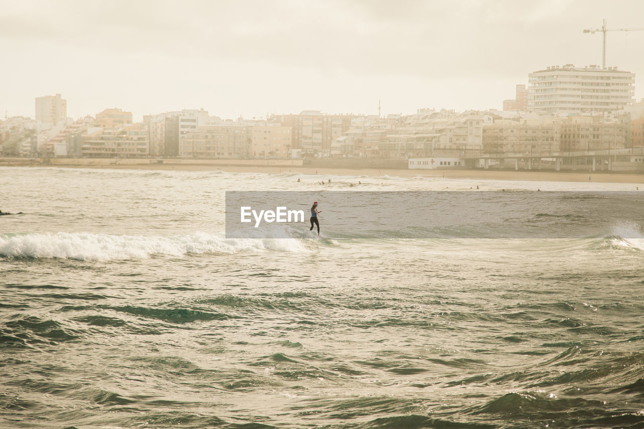 High angle view of woman surfing on sea against sky