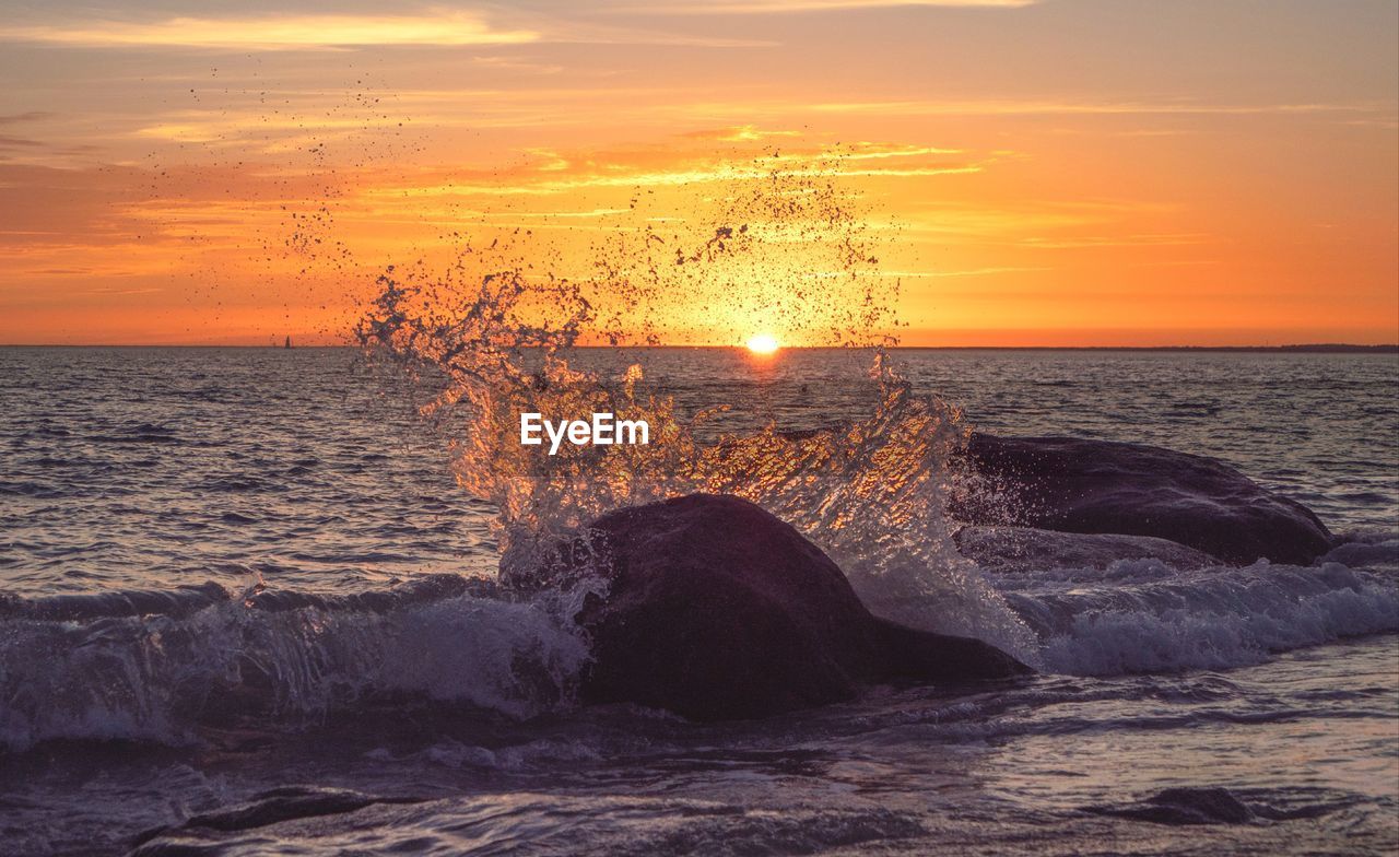 sea, sunset, water, sky, ocean, beauty in nature, wave, horizon over water, shore, scenics - nature, motion, horizon, land, nature, wind wave, coast, beach, orange color, dawn, cloud, sun, rock, sports, seascape, no people, idyllic, tranquility, splashing, evening, body of water, outdoors, water sports, tranquil scene, breaking, environment, sunlight, afterglow, travel destinations, dramatic sky