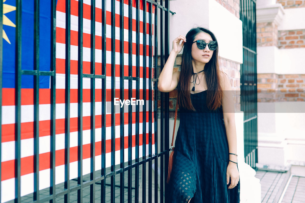 Young woman standing by fence