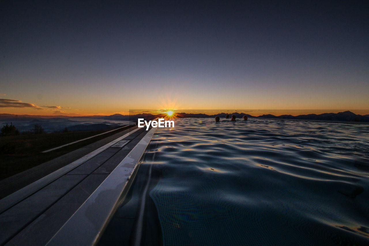 People in swimming pool at sunset