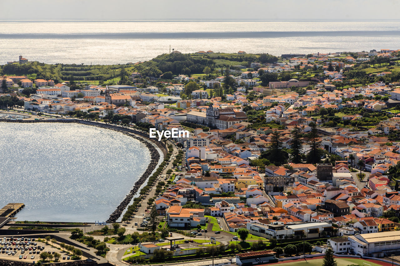 High angle view of townscape by sea against sky