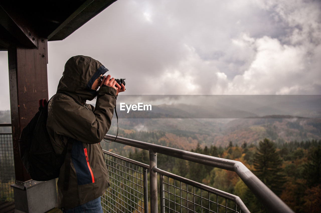 Side view of man photographing while standing at observation point