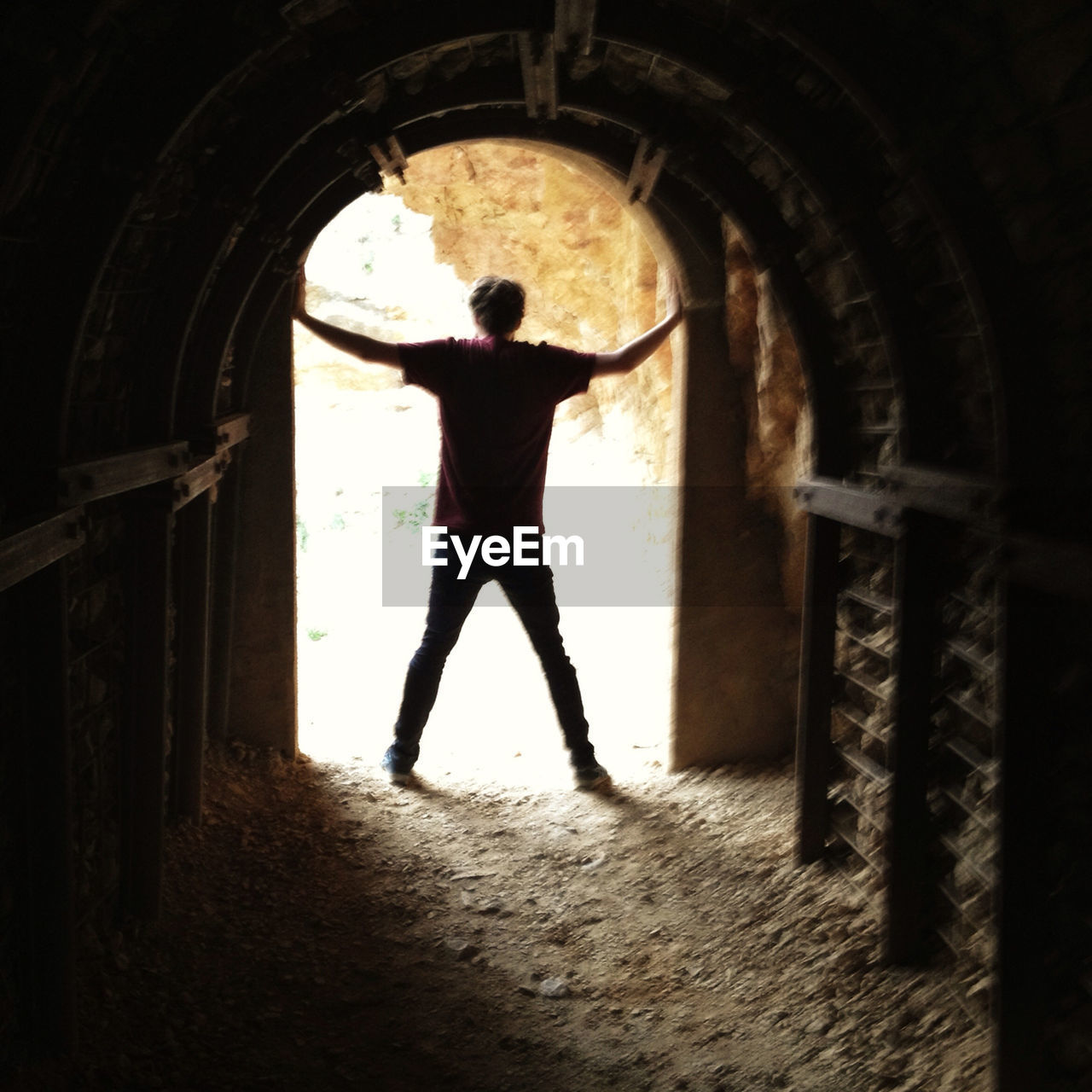 Rear view of man standing at entrance of archway