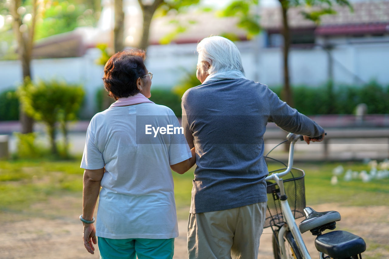 A senior couple is happily riding their bicycles in the park in the morning.