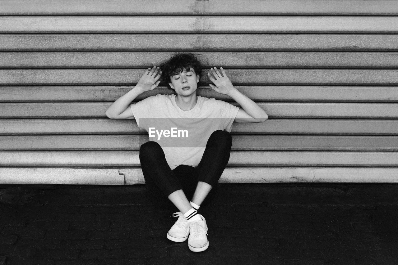 FULL LENGTH PORTRAIT OF GIRL SITTING ON WALL