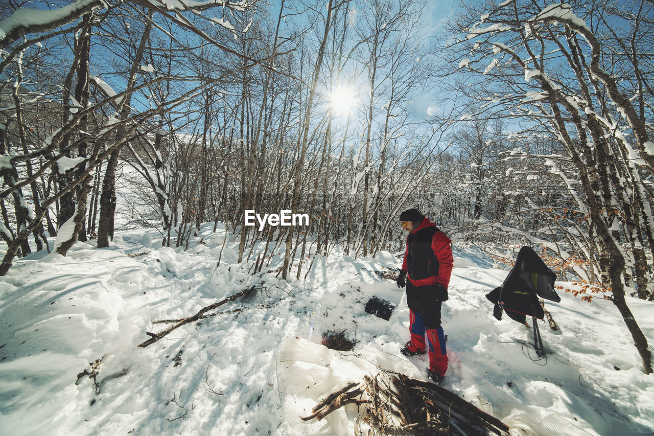 Man standing on snow against bare trees in forest
