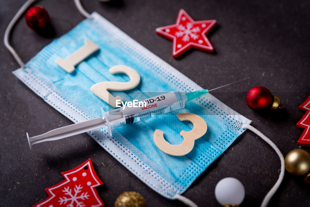 Third covid vaccine dose and jab concept with face mask and numbers and christmas decorations.