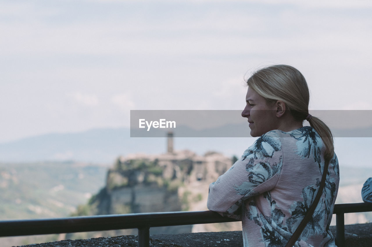 Side view of woman looking away against sky