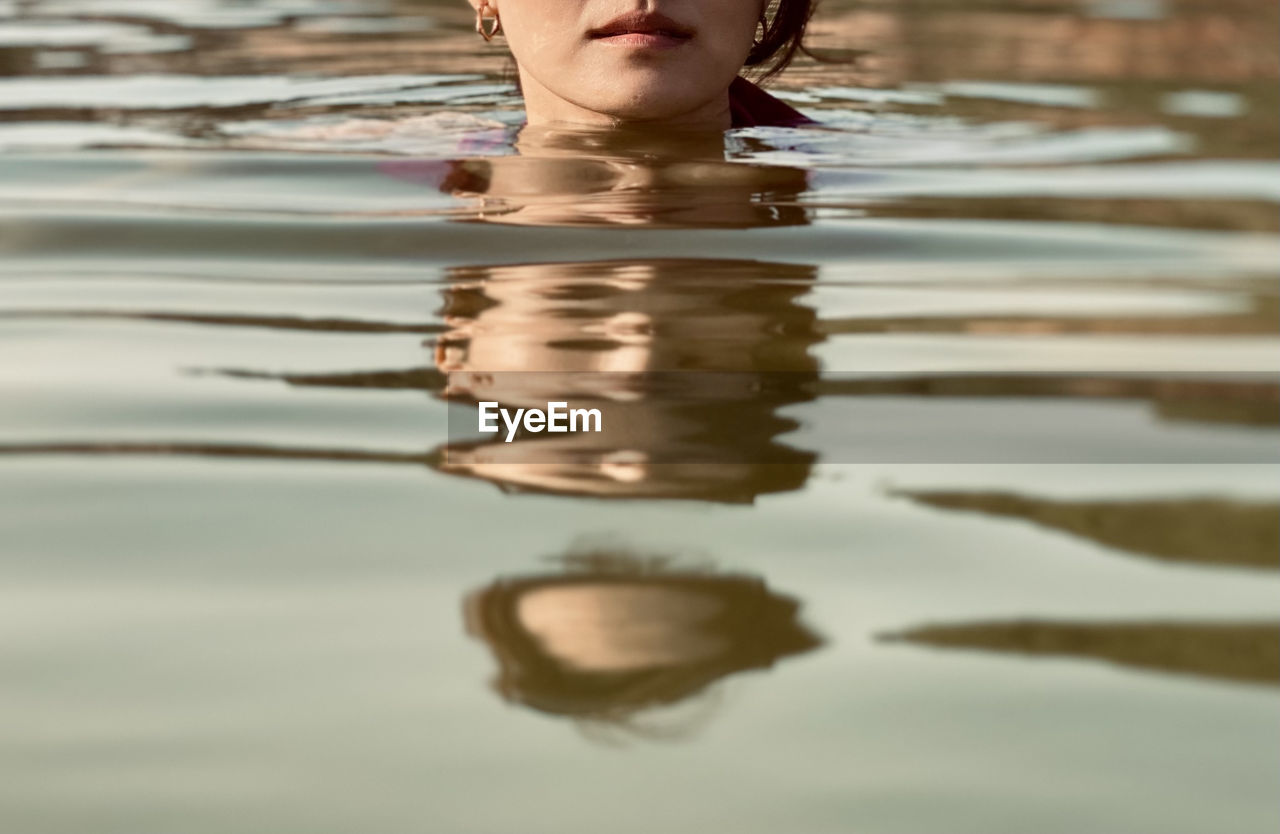 Low section of woman with reflection in water