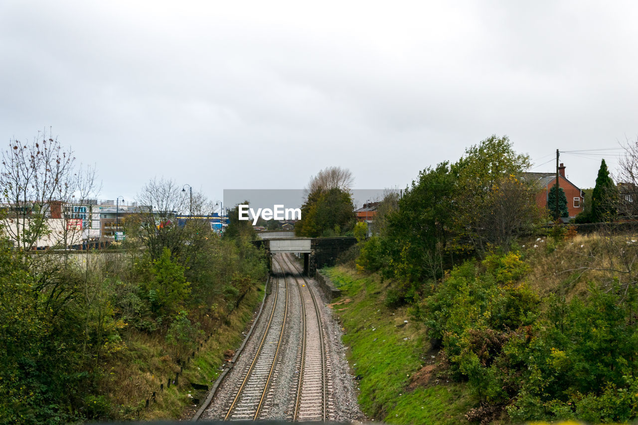 RAILROAD TRACK BY TREES AGAINST SKY