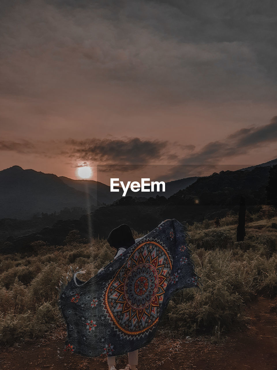 Rear view of woman standing against sky during sunset