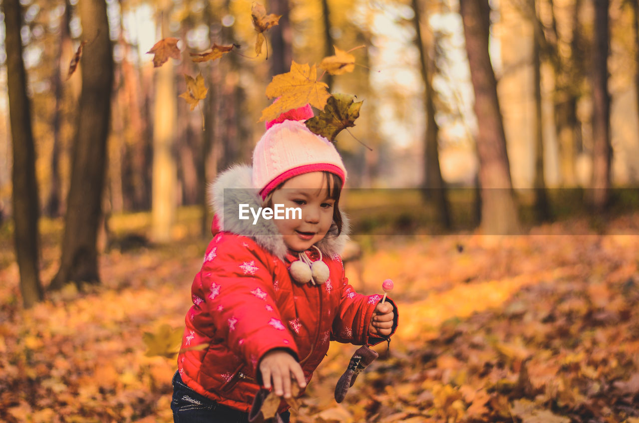 Pretty girl playing with yellow leaves in the autumn forest