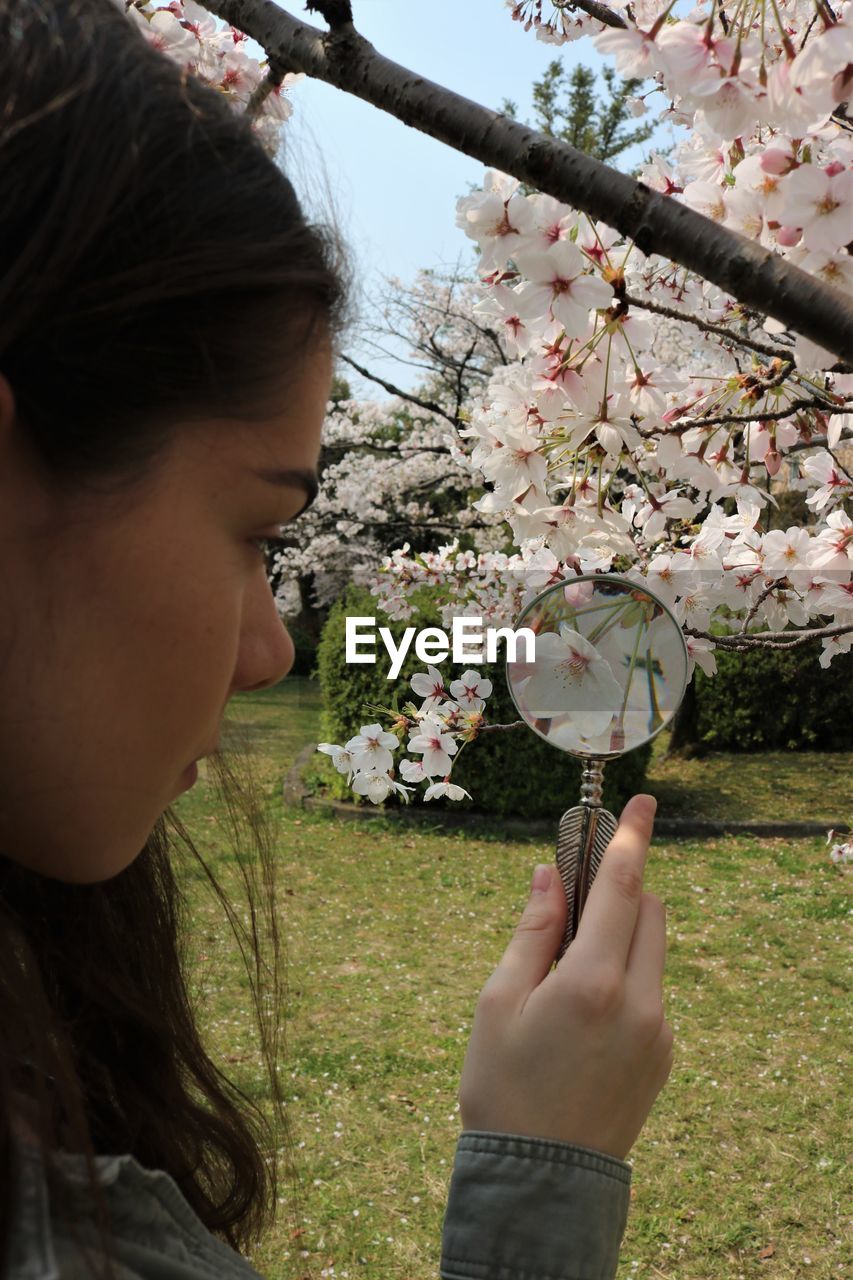 CLOSE-UP OF BEAUTIFUL WOMAN HOLDING CHERRY BLOSSOM