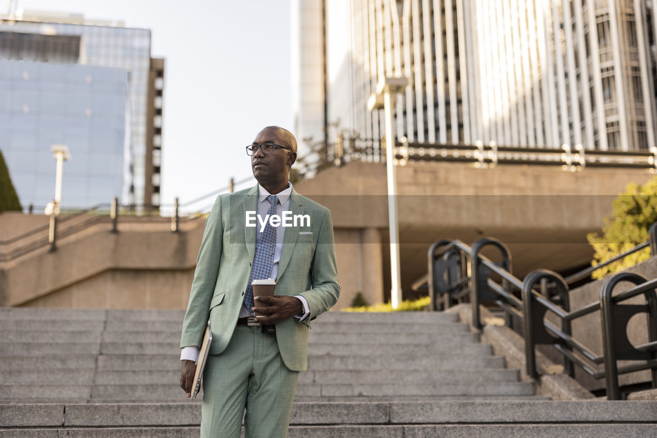 Mature businessman with laptop and coffee cup on steps