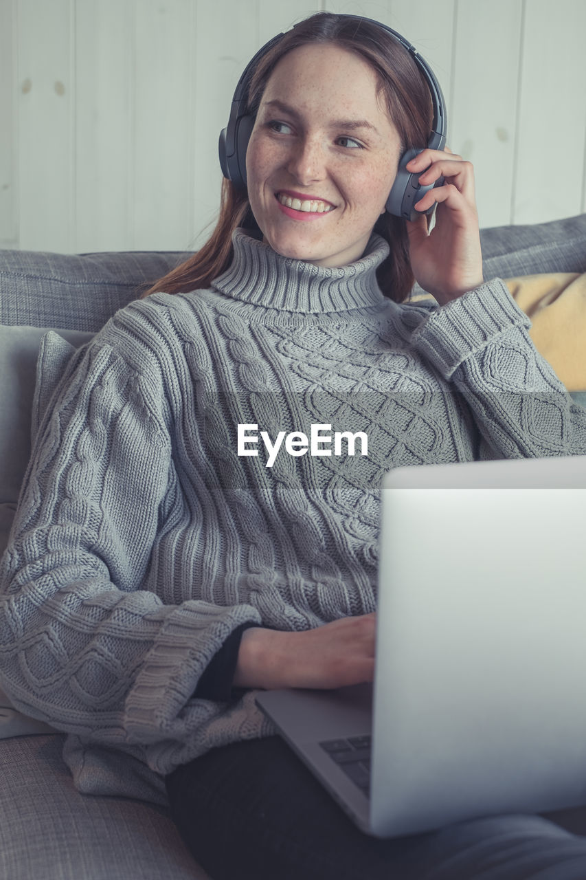 PORTRAIT OF A SMILING YOUNG WOMAN USING LAPTOP