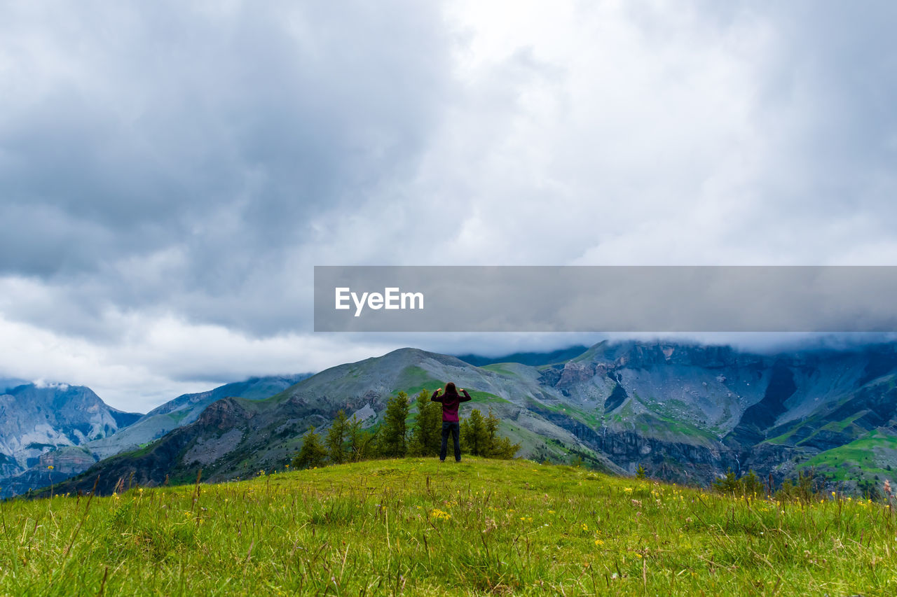 A young female hiker on a break during a hike on a cloudy summer day in the french alps