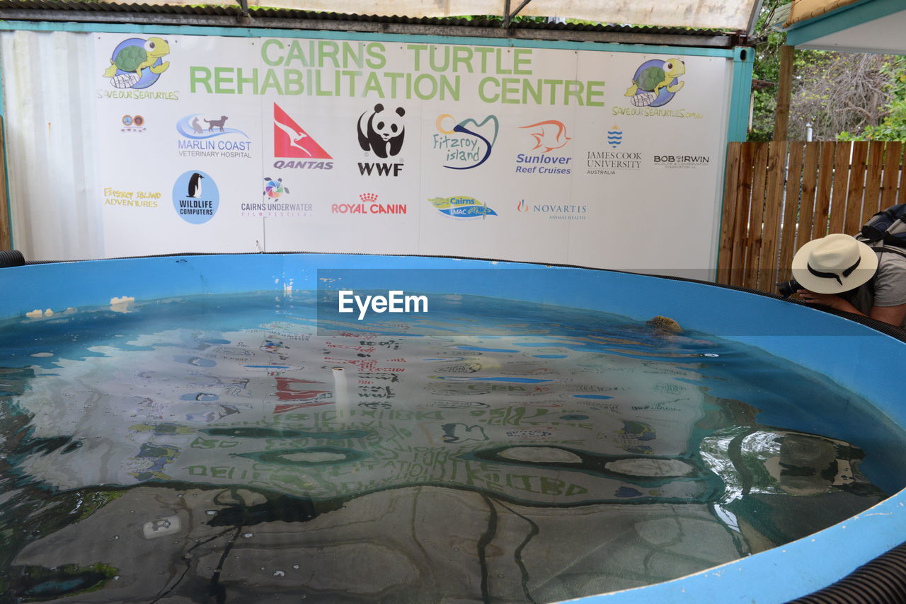 HIGH ANGLE VIEW OF INFORMATION SIGN BY SWIMMING POOL