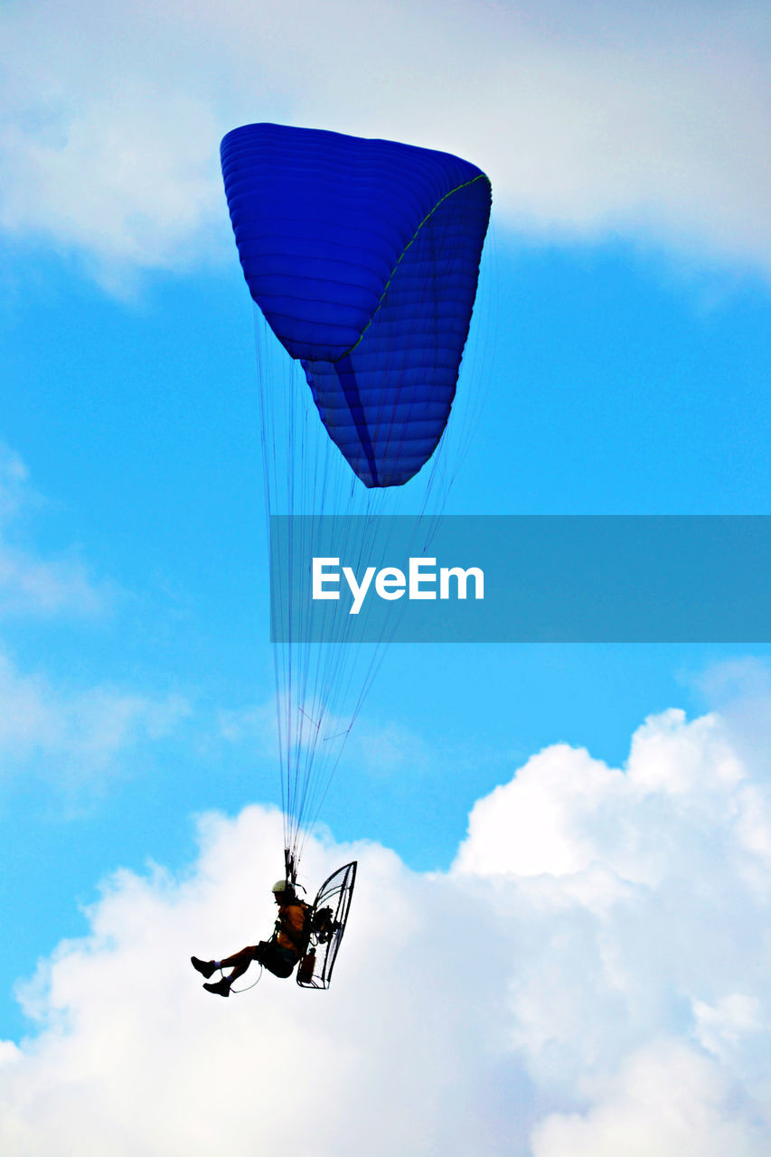 Person motor paragliding against sky