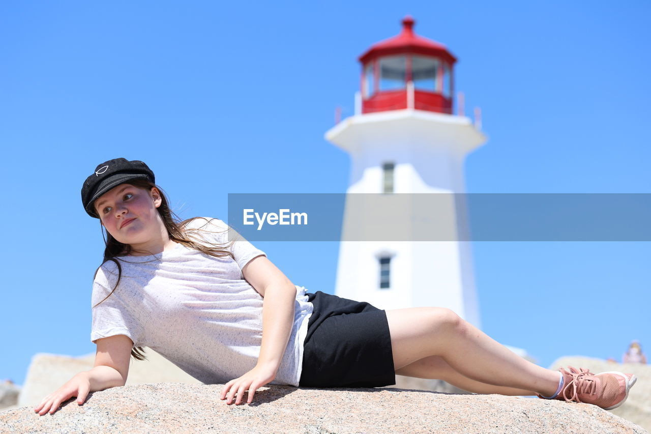 Low angle view of lighthouse against clear sky with girl in foreground.