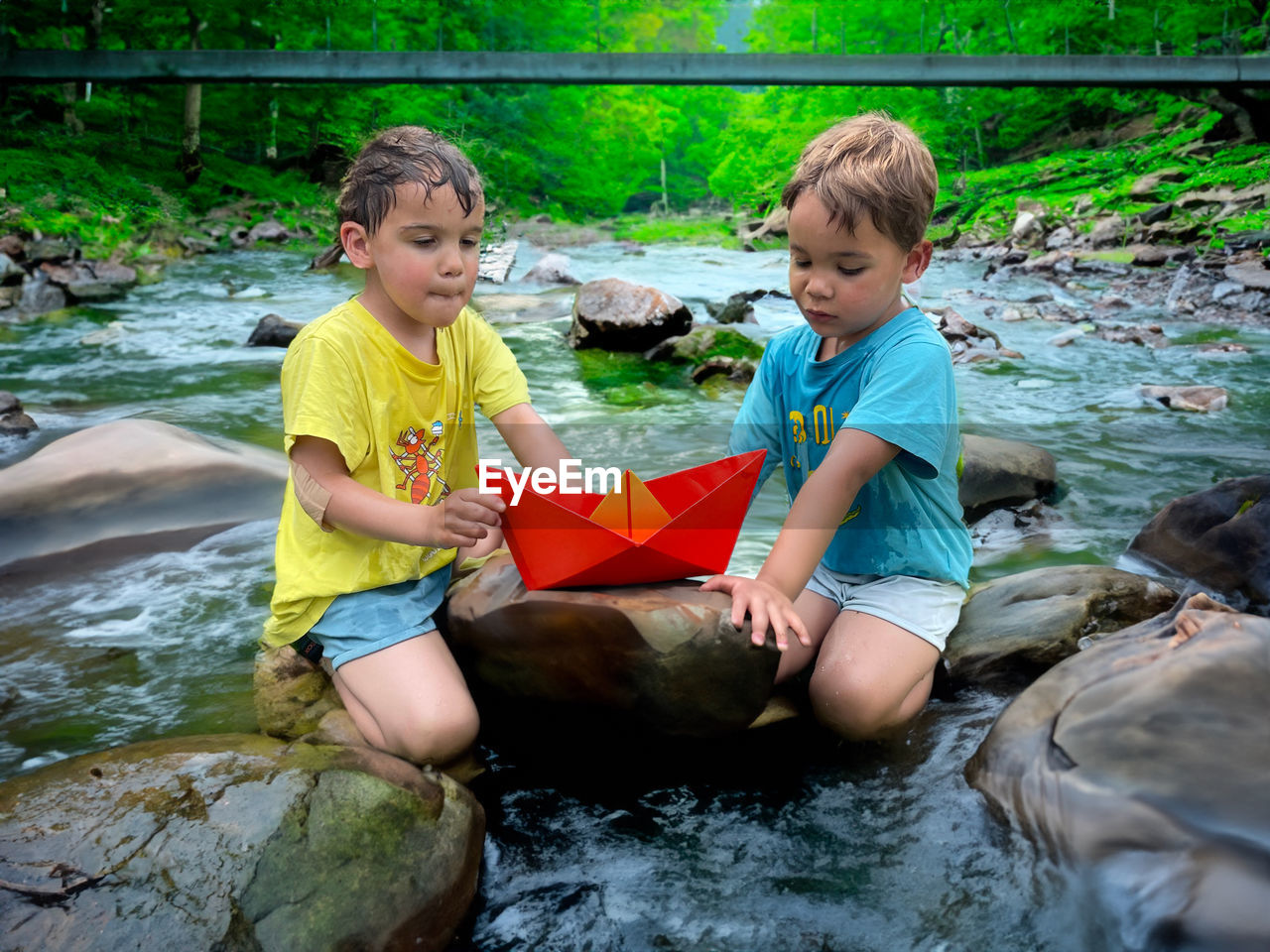 Side view of boys sitting in nature river