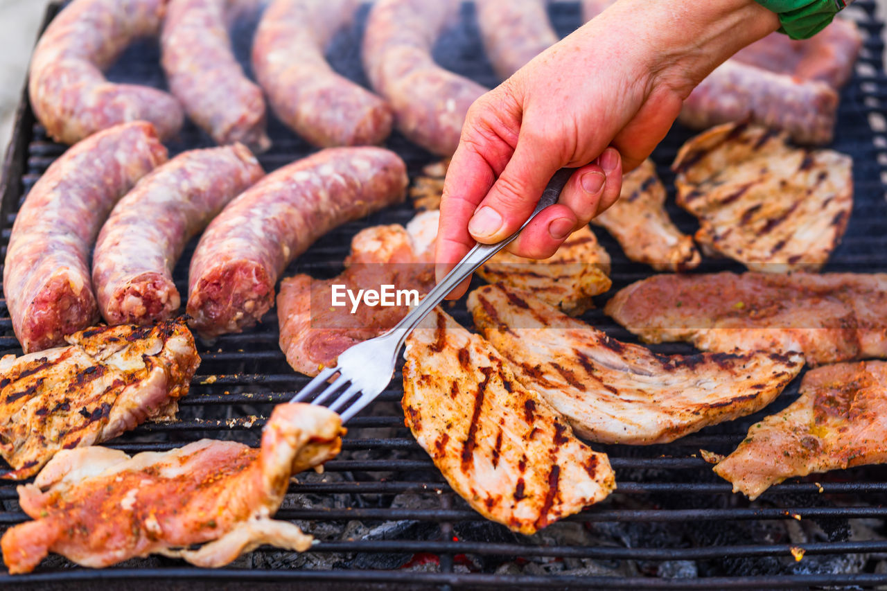 cropped hand of man preparing food on barbecue grill