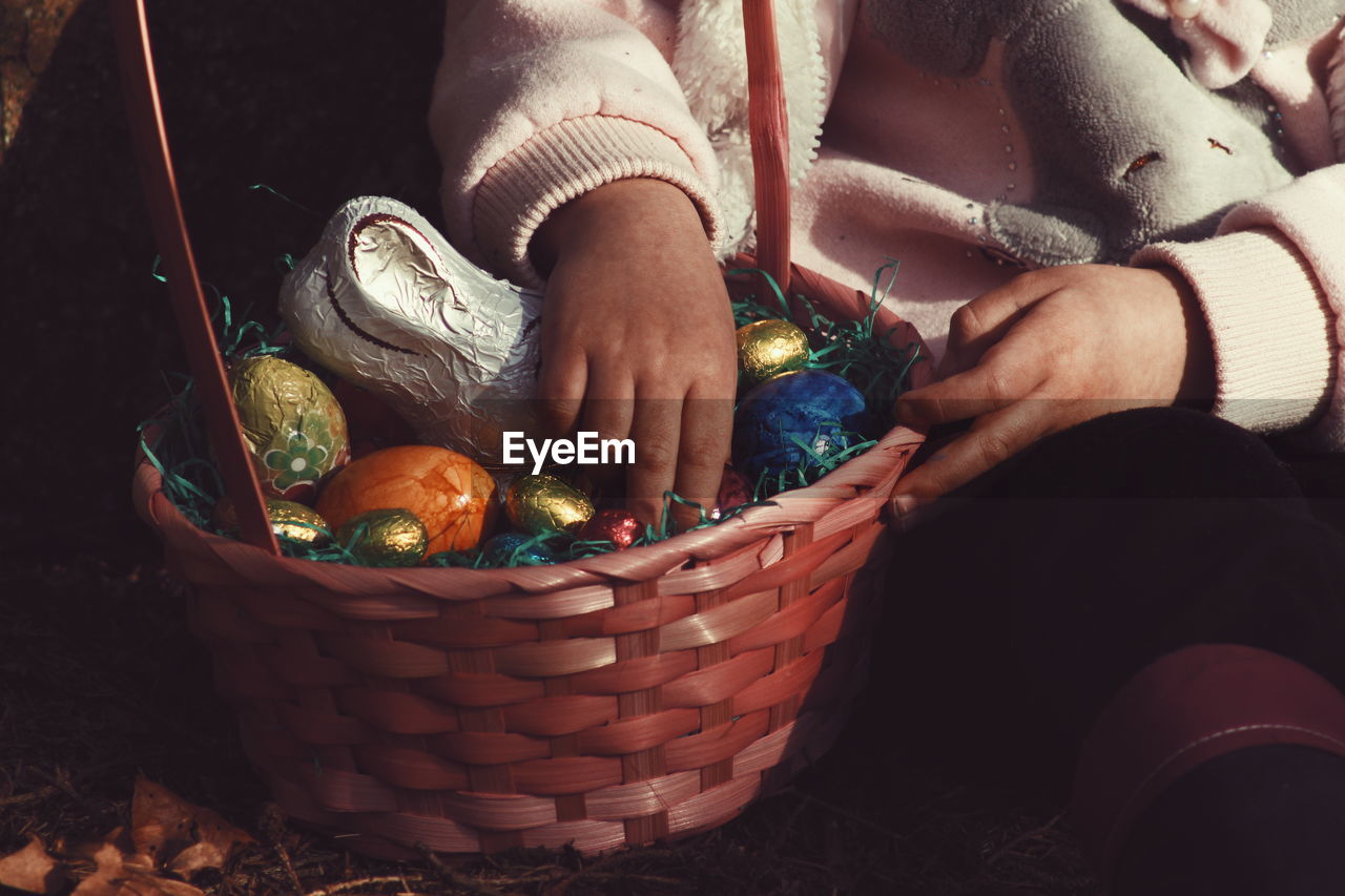 Midsection of person holding easter eggs in basket