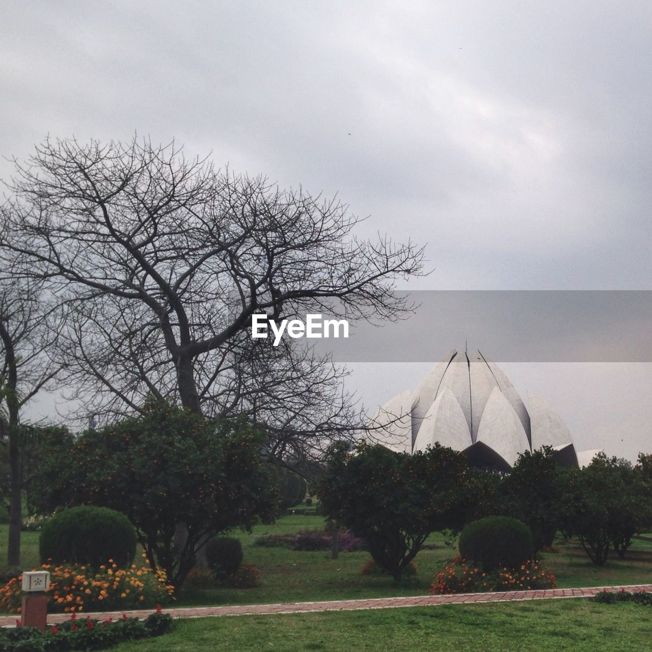 Lotus temple surrounded by formal garden against cloudy sky