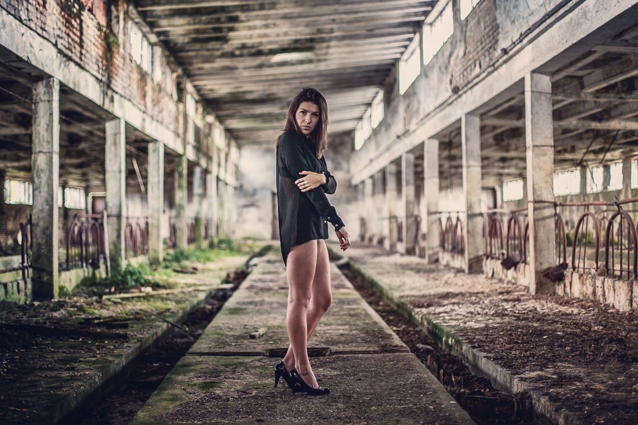 Portrait of beautiful woman standing on concrete in abandoned factory