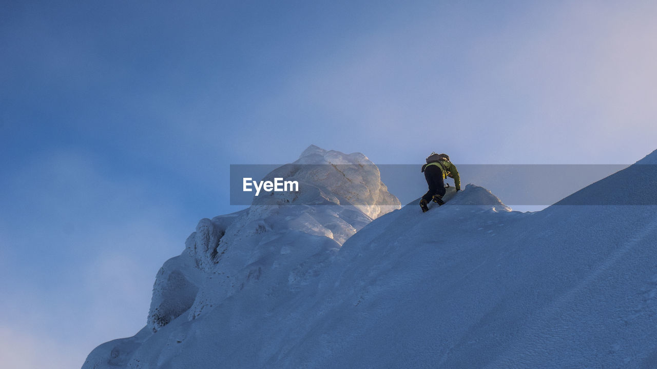 LOW ANGLE VIEW OF MAN SKIING ON MOUNTAIN AGAINST SKY