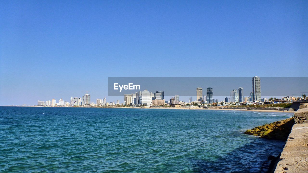 Sea and cityscape against clear blue sky