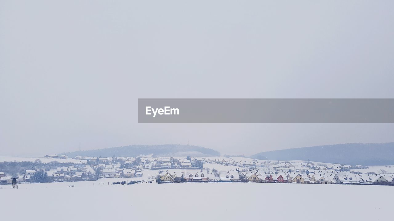 Scenic view of village against sky during winter