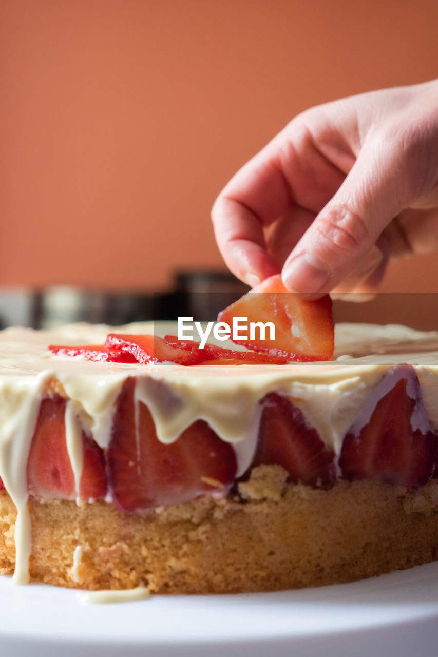 CLOSE-UP OF HAND HOLDING ICE CREAM WITH CAKE