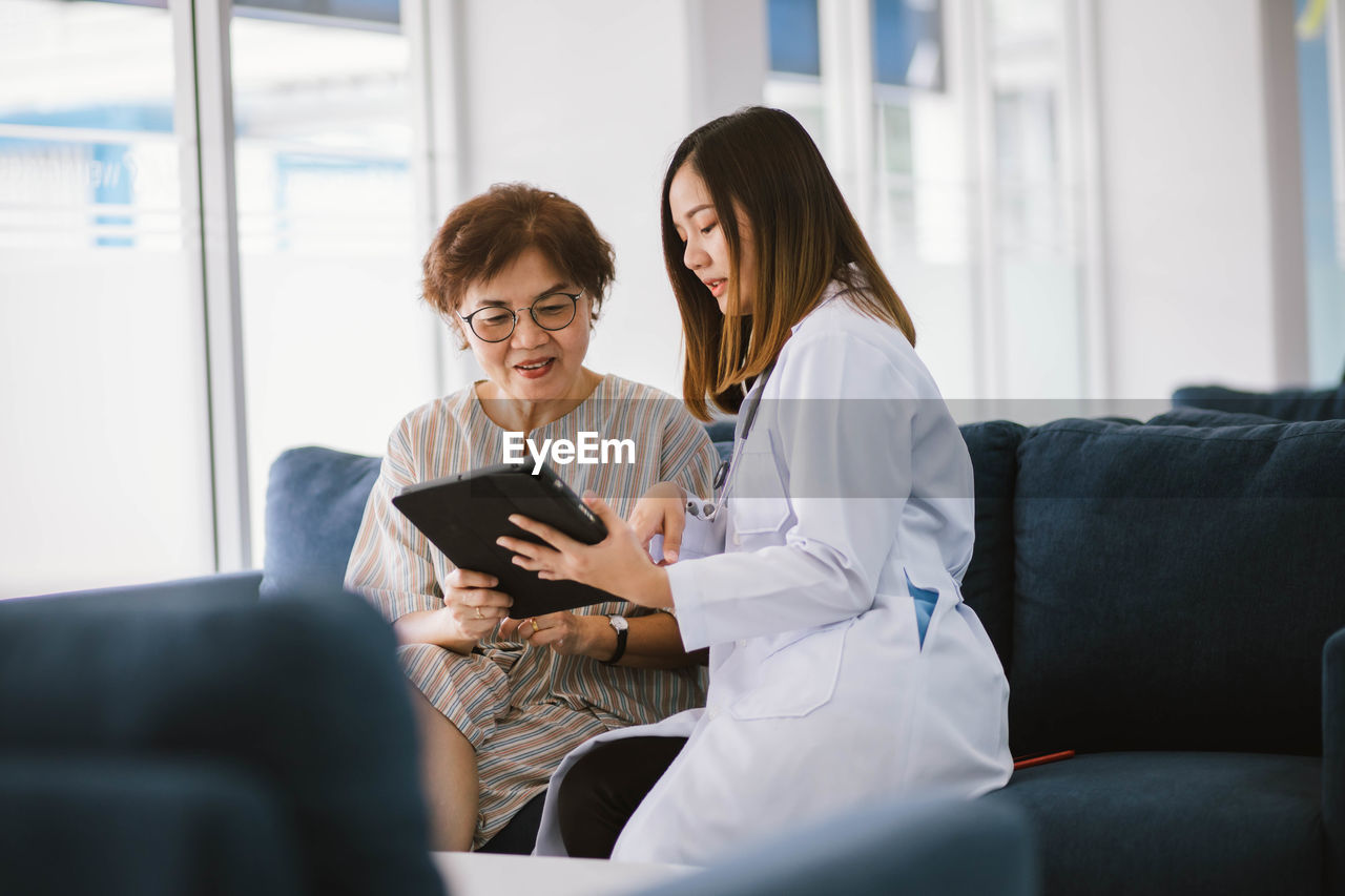 WOMEN SITTING ON SOFA IN LIVING ROOM