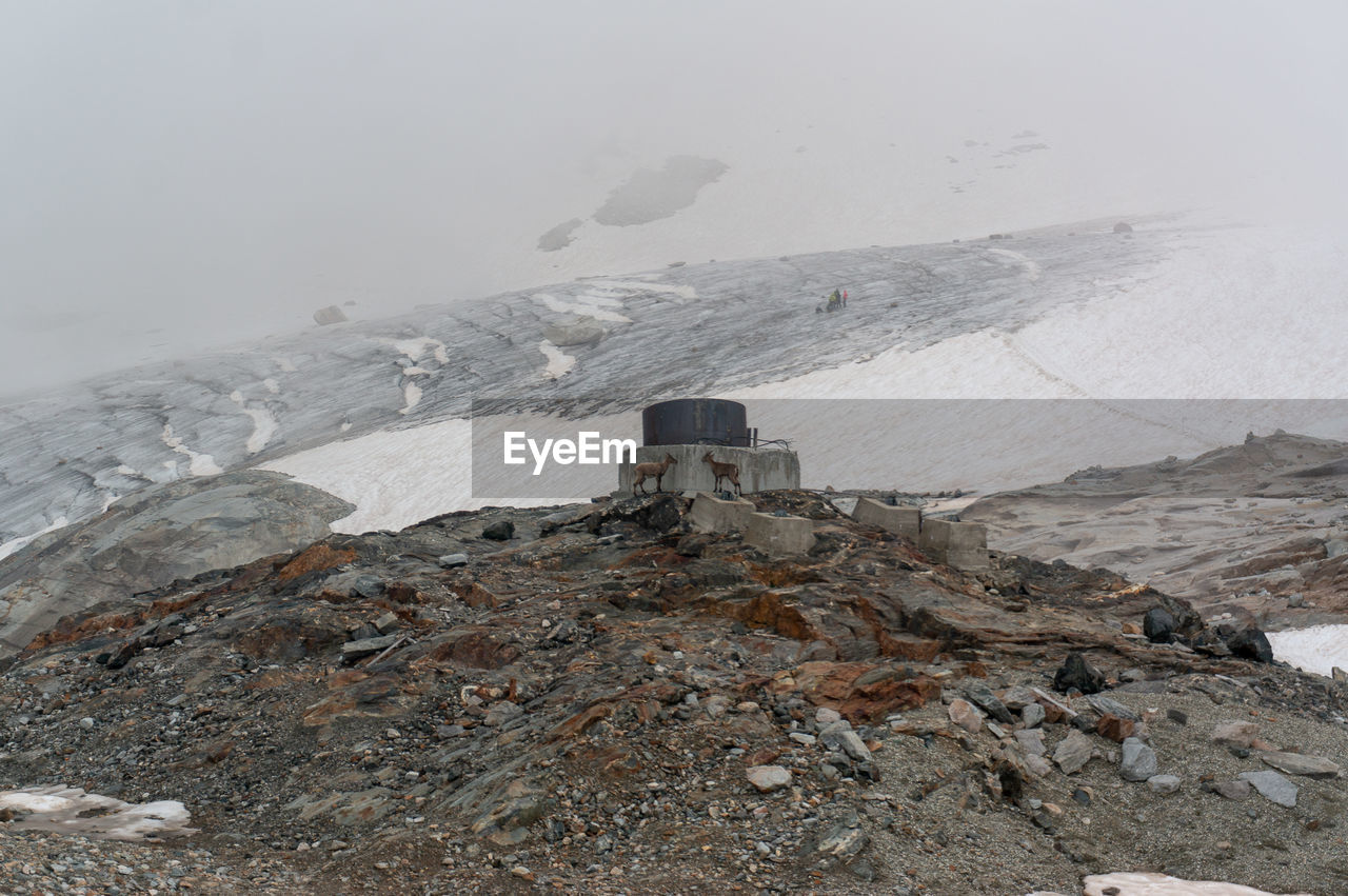 Built structure on snow covered mountain against sky