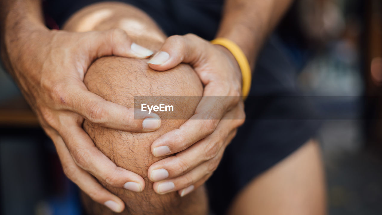 Midsection of man touching knee in pain