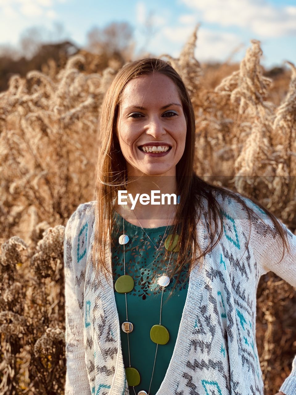Portrait of smiling young woman standing against plants