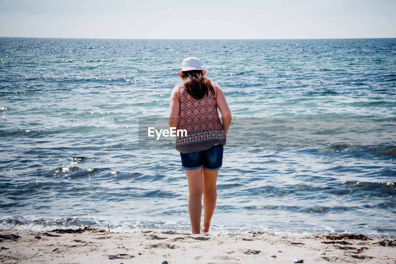 Rear view of woman standing at sea shore