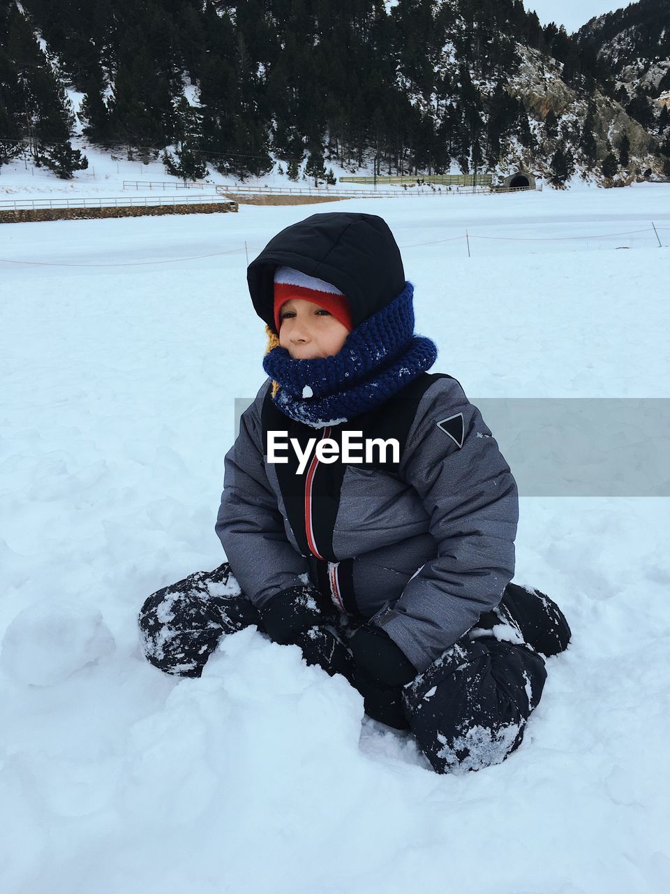 Cute boy in warm clothing playing with snow during winter