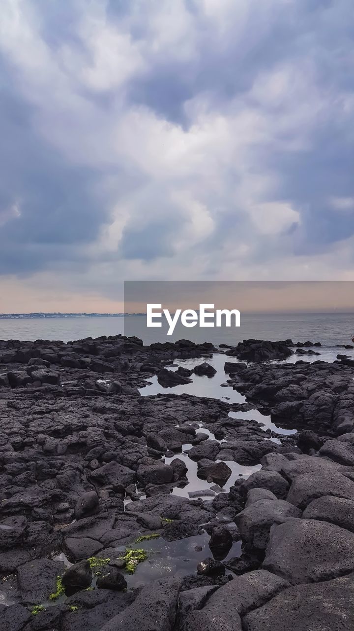 ROCKS ON SHORE AGAINST SKY