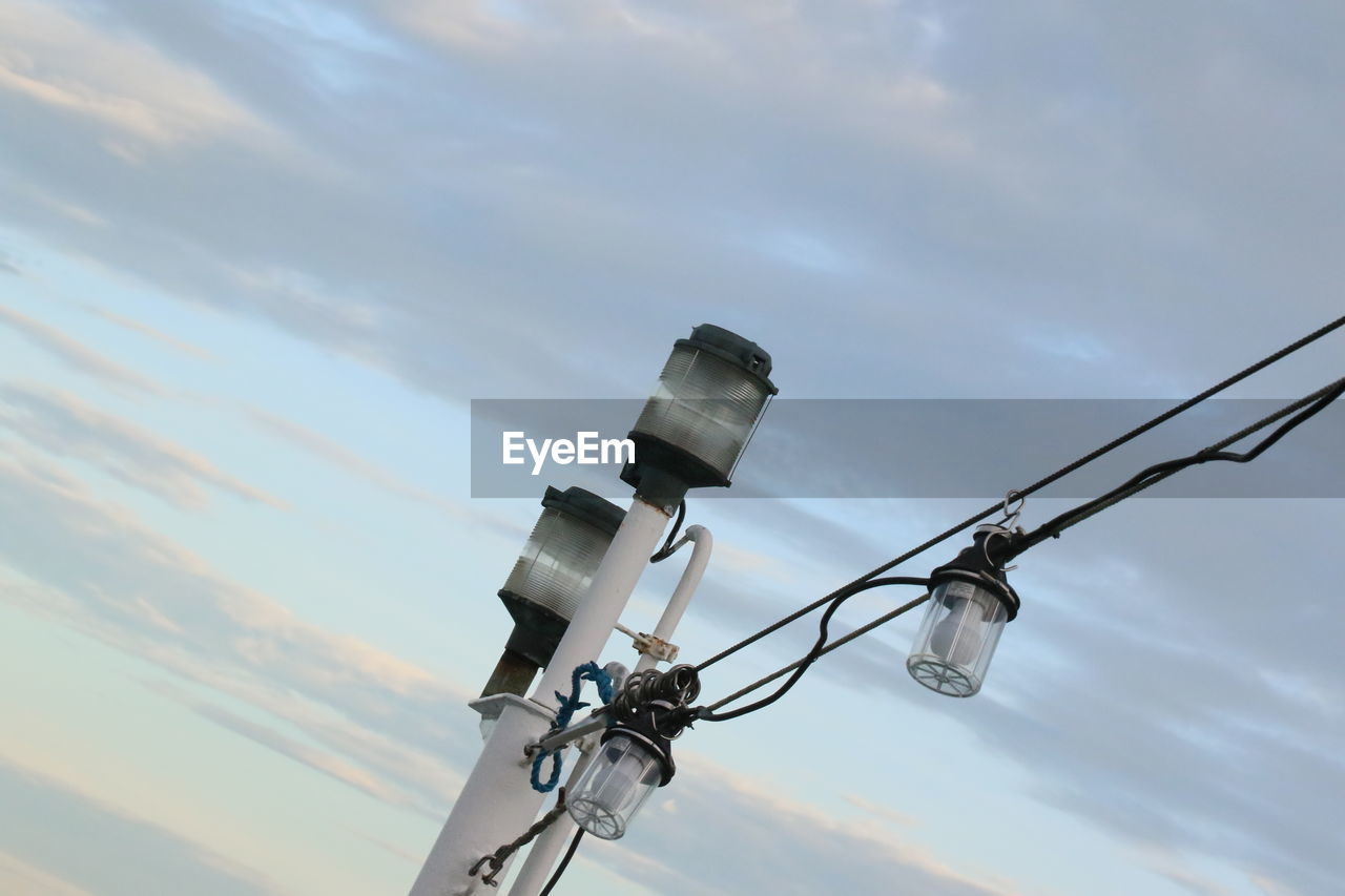 Low angle view of telephone pole against cloudy sky